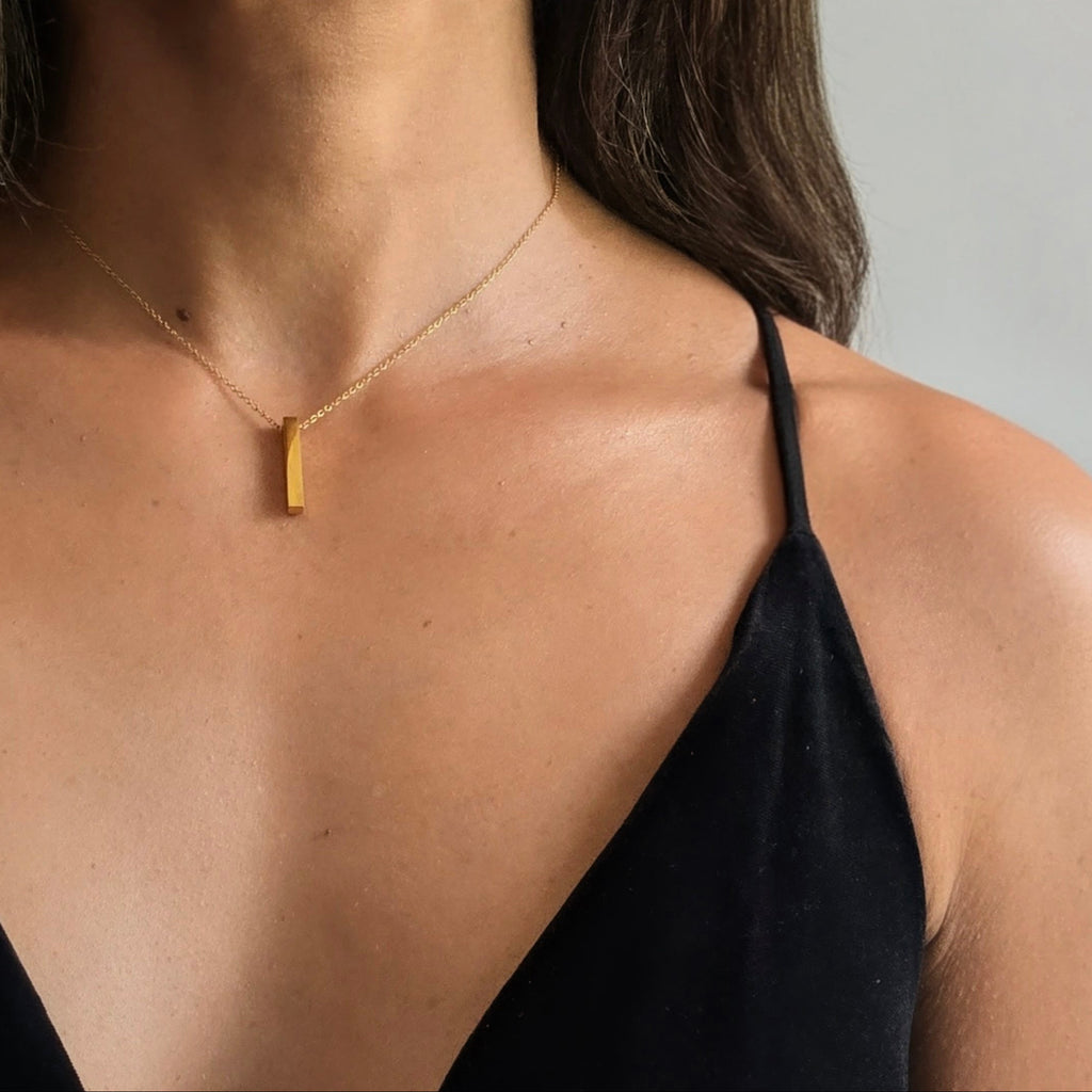 Woman wearing a gold necklace against a neutral background