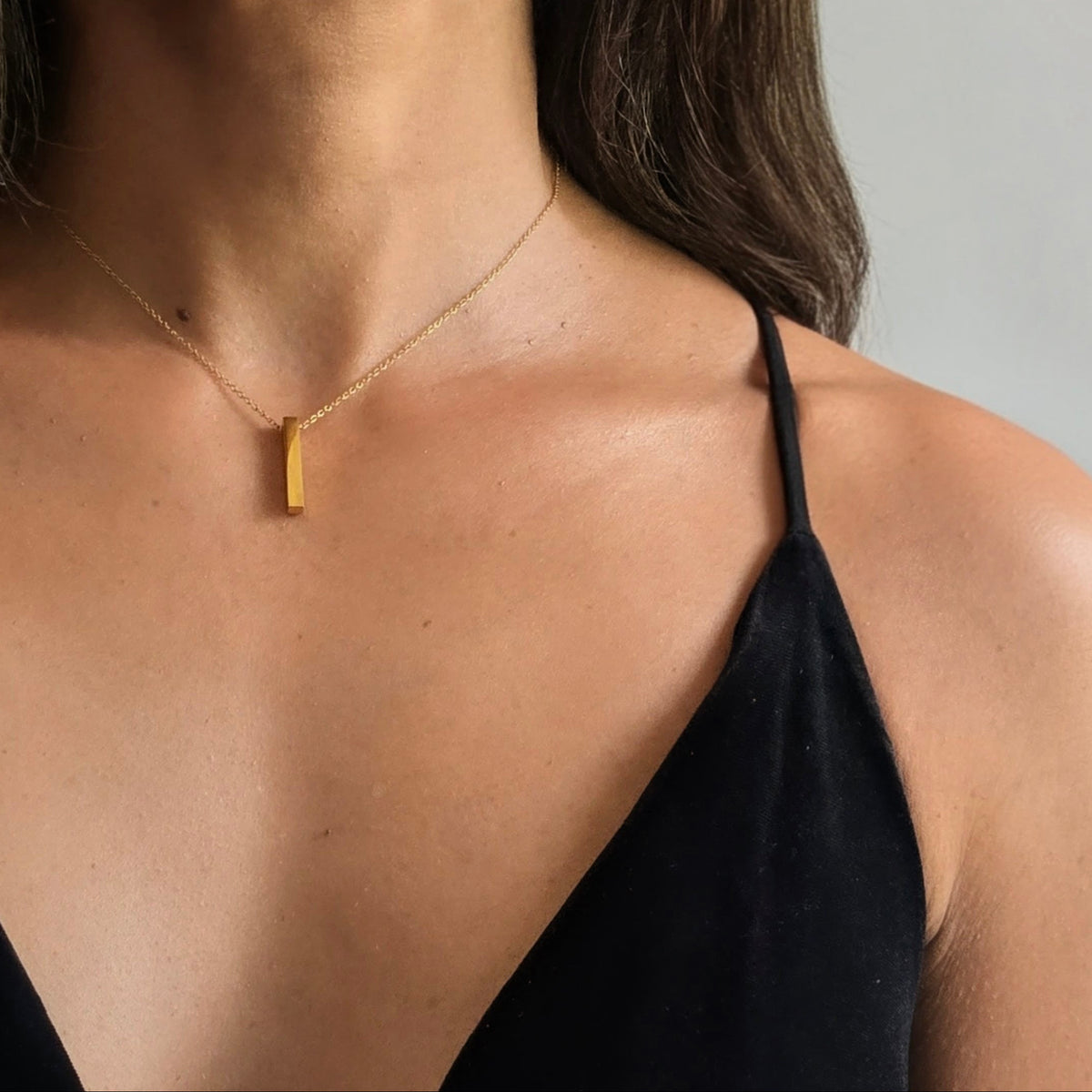 Woman wearing a gold necklace against a neutral background