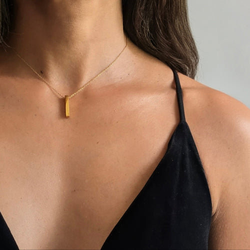 Woman wearing a gold necklace against a neutral background